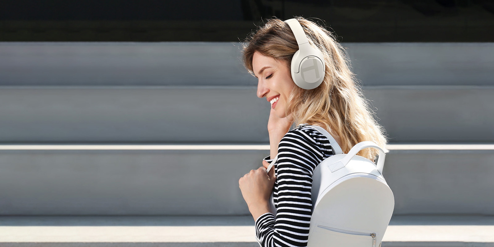 Mujer con mochila escuchando los auriculares Haylou S35 ANC