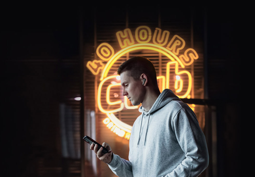 Foto de um homem com Haylou X1 Pro perto de publicidade de néon